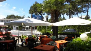 Area esterna con tavoli e sedie, ombrelloni e un cartello per 'S. Cruz Hotel'.