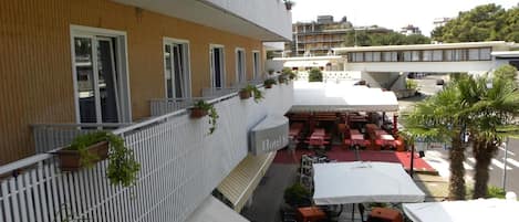 A hotel with outdoor seating, a wooden facade, and a white awning.