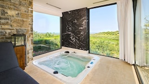 A room with a large bathtub, a stone wall, and a view of greenery. - Villa Zimzelen - Four Bedroom Villa, Sleeps 10 (Merišće)