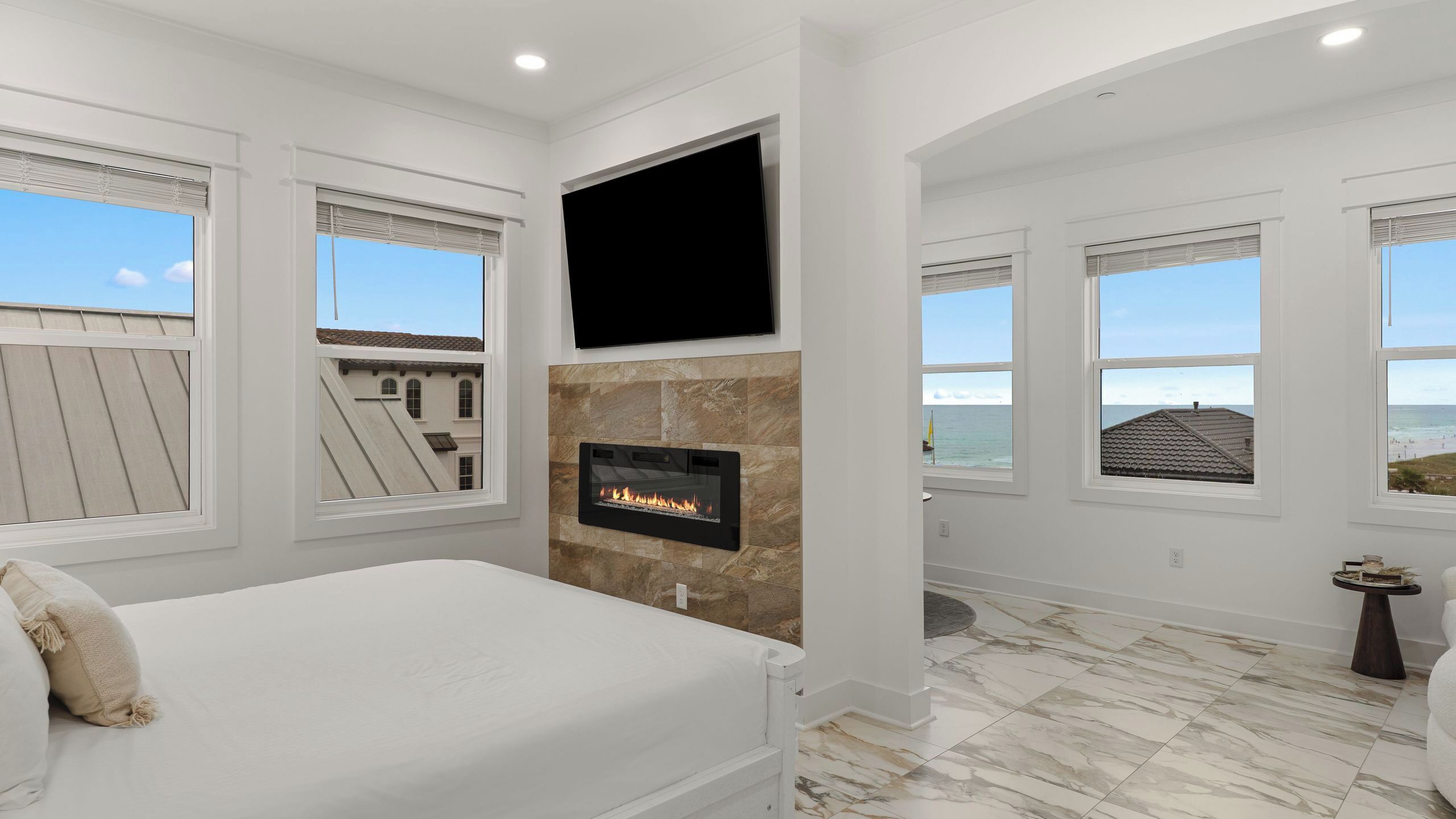 Un dormitorio con cama, chimenea, televisión y vista al océano.