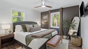 Une chambre à coucher avec un lit, une table de chevet, une lampe et un ventilateur de plafond.