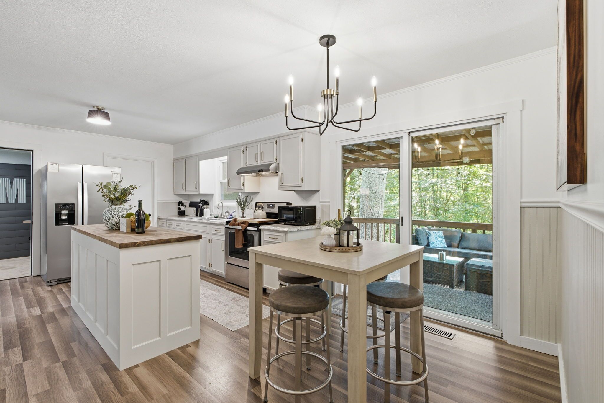 A modern kitchen with a central island, bar stools, and a dining table.