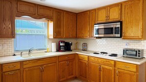 A kitchen with wooden cabinets, a microwave, a toaster, and a coffee maker. - 2BR Coastal Cottage – Minutes to Beach & Bay (Englewood)