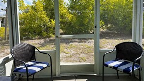 A screened porch with two chairs and a sliding glass door. - 2BR Coastal Cottage – Minutes to Beach & Bay (Englewood)