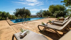 Un área junto a la piscina con sillones, una piscina y vistas de la ciudad.