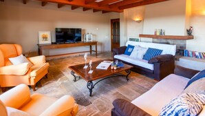 Una sala de estar con sofá, sillones, una mesa de centro, televisor y chimenea.