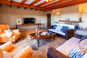 Ein Wohnzimmer mit einer Couch, Sesseln, einem Couchtisch, einem Fernseher und einem Kamin.