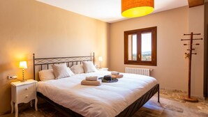 Un dormitorio con cama, mesitas de noche, lámpara, radiador, ventana y lámpara de pie.