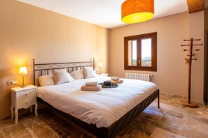 Ein Schlafzimmer mit Bett, Nachttischen, einer Lampe, einem Heizkörper, einem Fenster und einer Stehlampe.