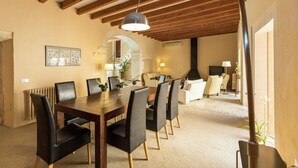 Ein Essbereich mit Holztisch und -stühlen, einer Chandelieber und einer Treppe, die in ein Wohnzimmer mit Kamin führt.