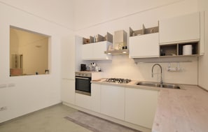 A modern kitchen with white cabinets, a gas stove, a built-in oven, a stainless steel sink, and a mirror. - 2 bedroom beautiful apartment in Loano (Loano)
