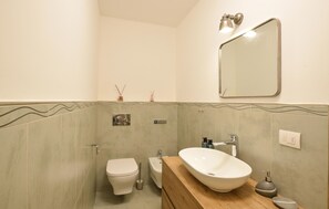 A bathroom with a toilet, bidet, and a sink with a mirror above. - 2 bedroom beautiful apartment in Loano (Loano)