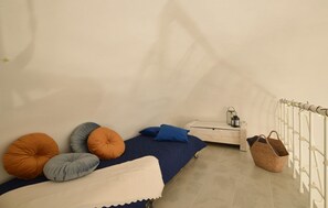 Ein kleines, gemütliches Zimmer mit Bett, Kissen, einem Nachttisch, einer Lampe und einer Heizung.
