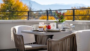 A dining table with chairs, a vase with flowers, and a view of mountains. - Bodenseezeit Apartmenthotel Garni (Wangen im Allgäu)
