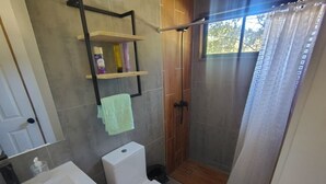 Un baño con inodoro, lavamanos y zona de ducha.
