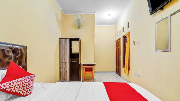 A hotel room with a bed, a desk, a wardrobe, a mirror, and a TV. - Flagship 90768 Endrayanti Inn Syariah (Yogyakarta)