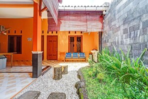 A courtyard with a bench, a tiled floor, a stone wall, and a sign indicating the area. - Flagship 90768 Endrayanti Inn Syariah (Yogyakarta)