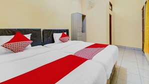 A hotel room with two beds, a wardrobe, a fan, and a door. - Flagship 90768 Endrayanti Inn Syariah (Yogyakarta)