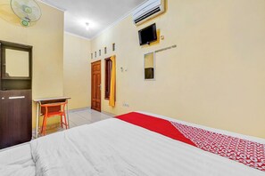 A room with a bed, a desk, a wardrobe, an air conditioner, and a television. - Flagship 90768 Endrayanti Inn Syariah (Yogyakarta)