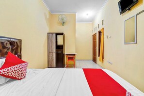 A hotel room with a bed, a desk, a wardrobe, a mirror, and a TV. - Flagship 90768 Endrayanti Inn Syariah (Yogyakarta)