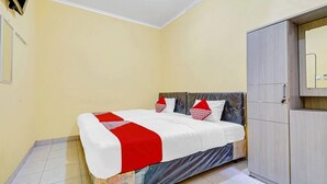 A bedroom with a bed, a wardrobe, and a tiled floor. - Flagship 90768 Endrayanti Inn Syariah (Yogyakarta)