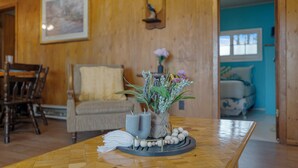 A wooden dining table with a vase of flowers, a candle holder, and a decorative plate. - Sandy Shores Cabin on Lake St. Peter with Fire Pit+BBQ (Lake Saint Peter)