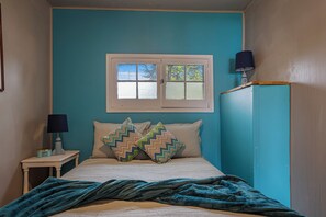Une chambre à coucher avec un lit, deux oreillers, une table de chevet avec une lampe et une fenêtre.