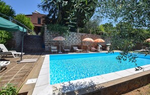A swimming pool with lounge chairs and umbrellas, surrounded by stone walls and greenery. - Awesome home in Corchiano (Corchiano)
