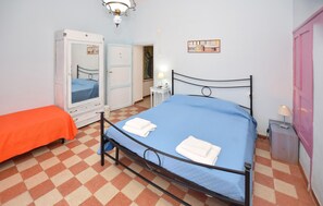 A bedroom with a checkered floor, a bed with a blue bedspread, a white wardrobe, and a pink door. - Awesome home in Corchiano (Corchiano)