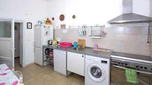 Eine kleine Küche mit Kühlschrank, Waschmaschine, Backofen und Spüle.