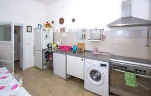 Eine kleine Küche mit Kühlschrank, Waschmaschine, Backofen und Spüle.