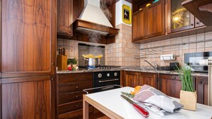 A kitchen with wooden cabinets, a stove, and a countertop with various items. - Italianway Easy - Corso San Gottardo 5 (Milano)