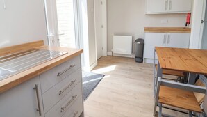 Eine moderne Küche mit einer Holz Arbeitsplatte, grauen Schränken, einem Heizkörper und einem Mülleimer.