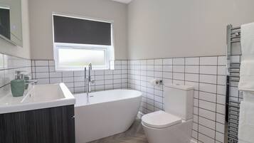 Un baño moderno con una bañera independiente, un inodoro y un ventanal.