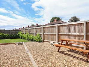 Ein Holzzaun, eine Schotterterrasse und eine hölzerne Bank.