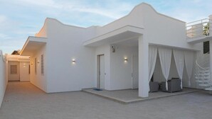 Een wit gebouw met een overdekt terras en een deur.