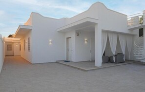 Ein weißes Gebäude mit überdachter Außenbestuhlung und einem Eingang.