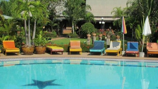 Una piscina con sillas de descanso y plantas en macetas.