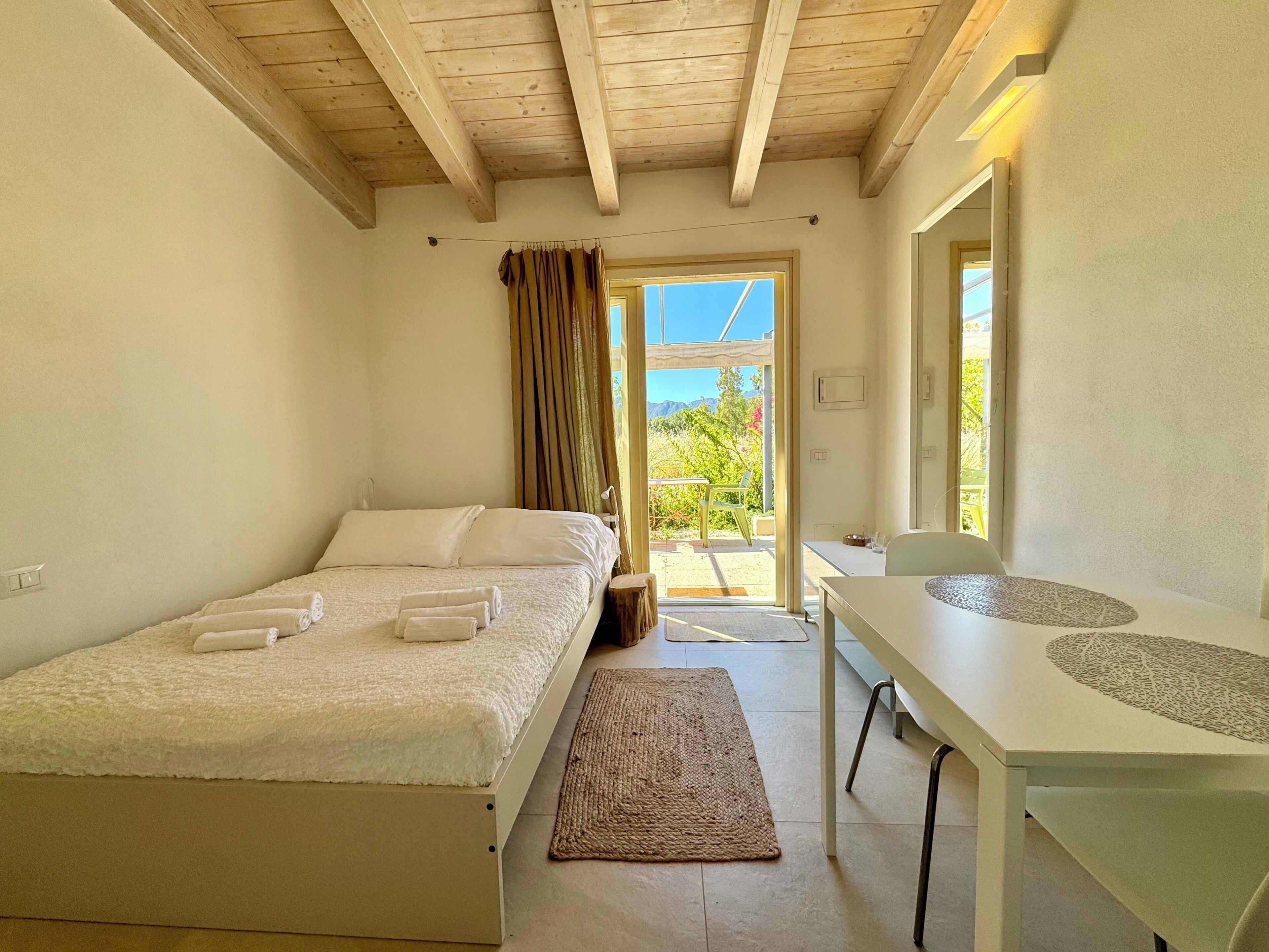Une chambre à coucher avec un lit, un bureau et une vue sur l’extérieur.