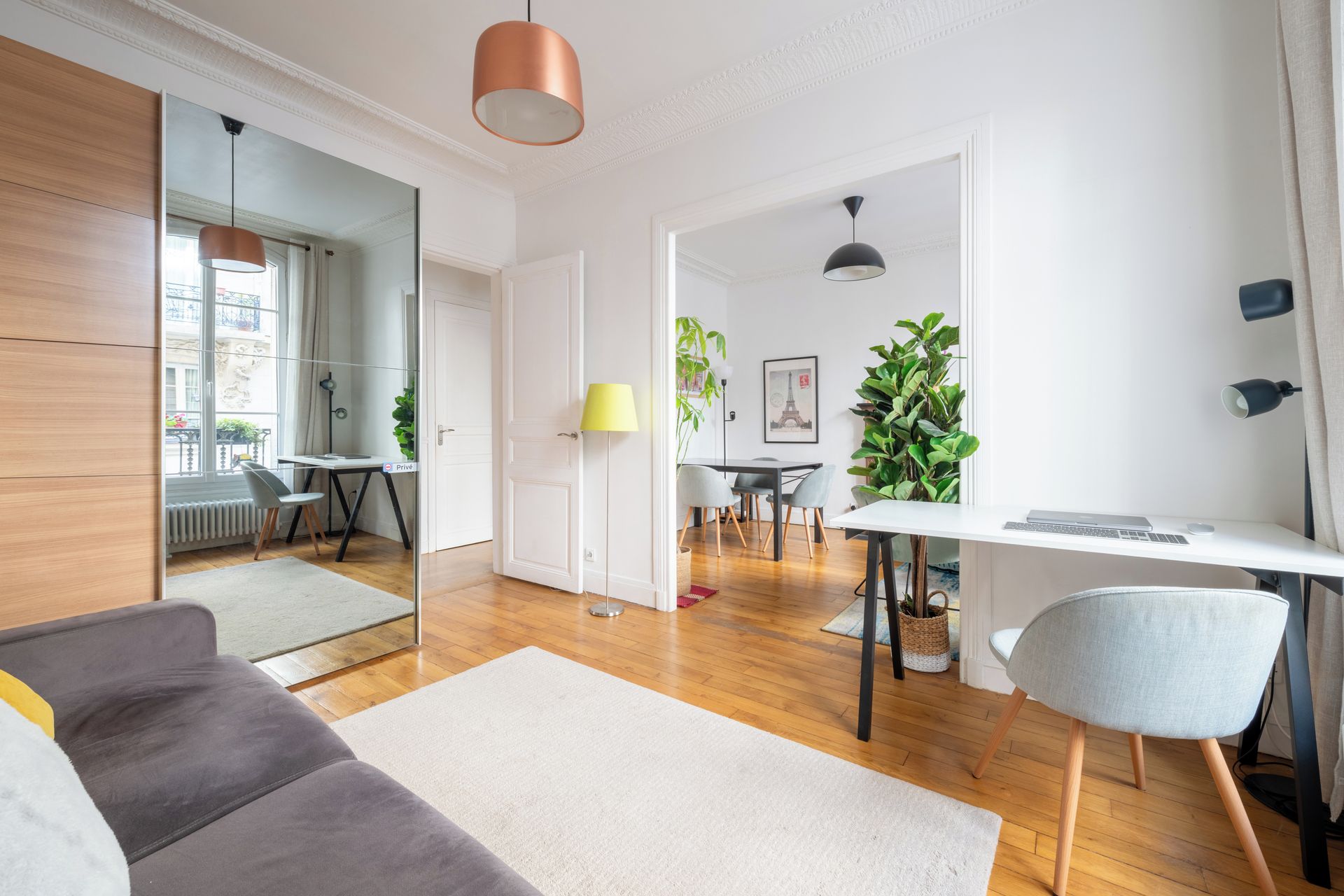 Una sala de estar moderna con un sofá, un comedor con sillas, una mesa y un escritorio con una computadora portátil.