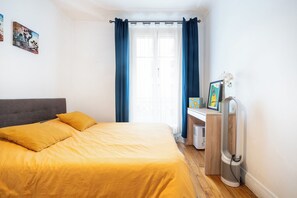 A bedroom with a bed, a desk, and a radiator. - Charming 1BDR Apartment for 3 Near Eiffel Tower (Paris)
