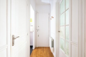 A hallway with white doors, a radiator, and a wooden floor. - Charming 1BDR Apartment for 3 Near Eiffel Tower (Paris)
