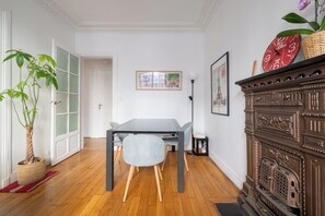 A dining area with a table, chairs, a decorative cabinet, and a potted plant. - Charming 1BDR Apartment for 3 Near Eiffel Tower (Paris)