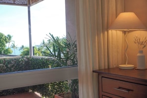 Ein Zimmer mit Fensterblick auf einen Garten, ein Nachttisch mit Lampe und ein Holznachttisch.