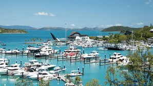 Uma marina com barcos atracados, um edifício com telhado inclinado e um céu azul límpido.