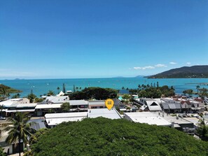 A coastal town with buildings, a clear blue sky, and a view of the sea with boats. - The Balcony at Airlie (Airlie Beach)