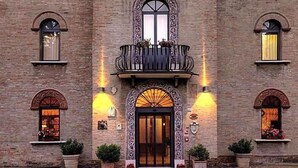 Un edificio con un ingresso centrale, due balconi con ringhiere e due finestre con tende.
