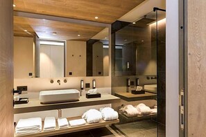 Un baño moderno con un espejo grande, un lavamanos y una zona de ducha.