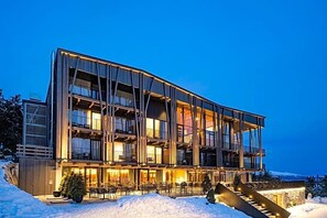 A multi-story hotel with balconies, outdoor seating, and a staircase leading to the entrance. - Olangerhof Hotel Spa (Valdaora)