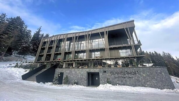 Ein modernes Gebäude mit Glasfassade, Steinsockel und einer Treppe zum Eingang.